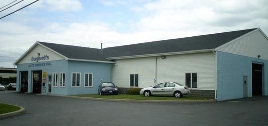 Exterior of a blue and white auto service building with cars parked outside.